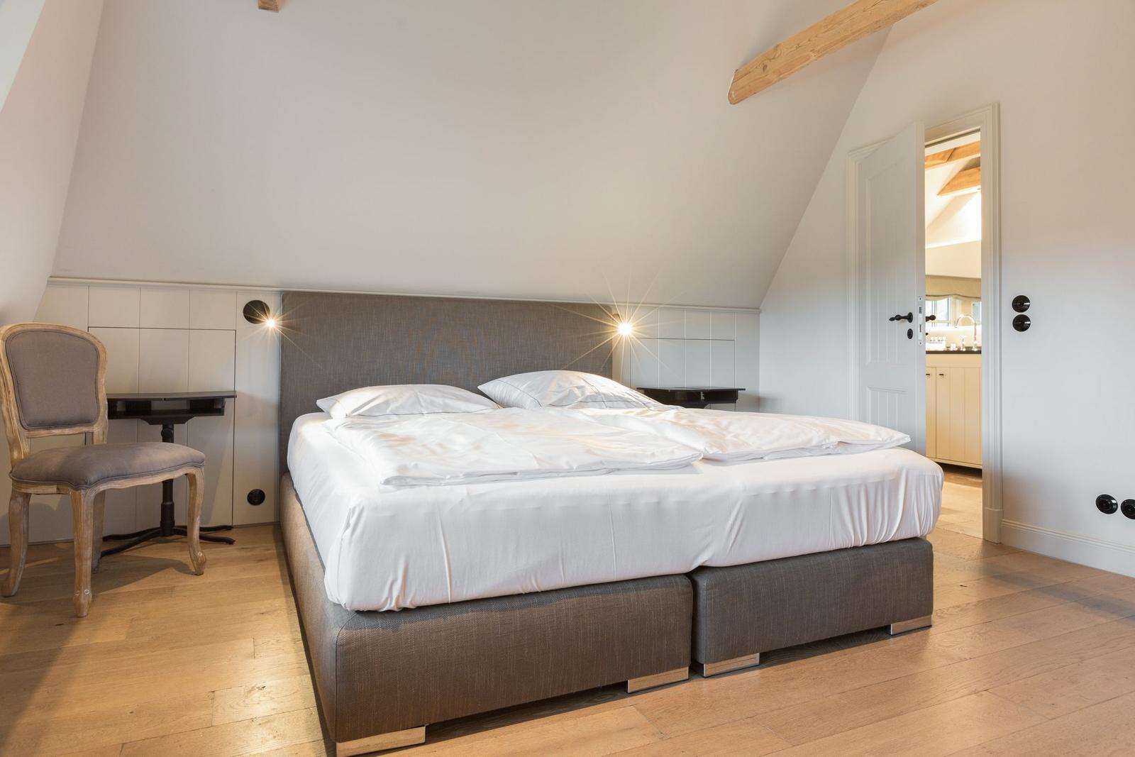 Schlafzimmer mit Doppelbett, Holzboden und schräger Decke mit Balken.
