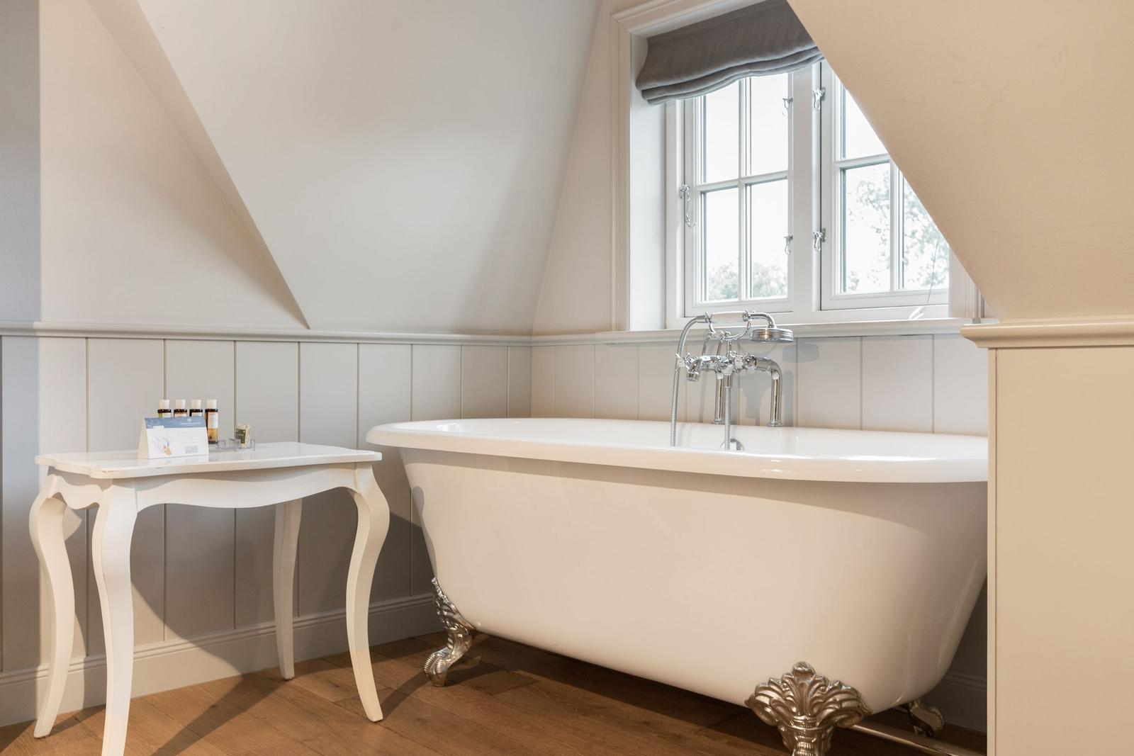 Bad mit freistehender Badewanne, Holzboden und Fenster mit Blick.