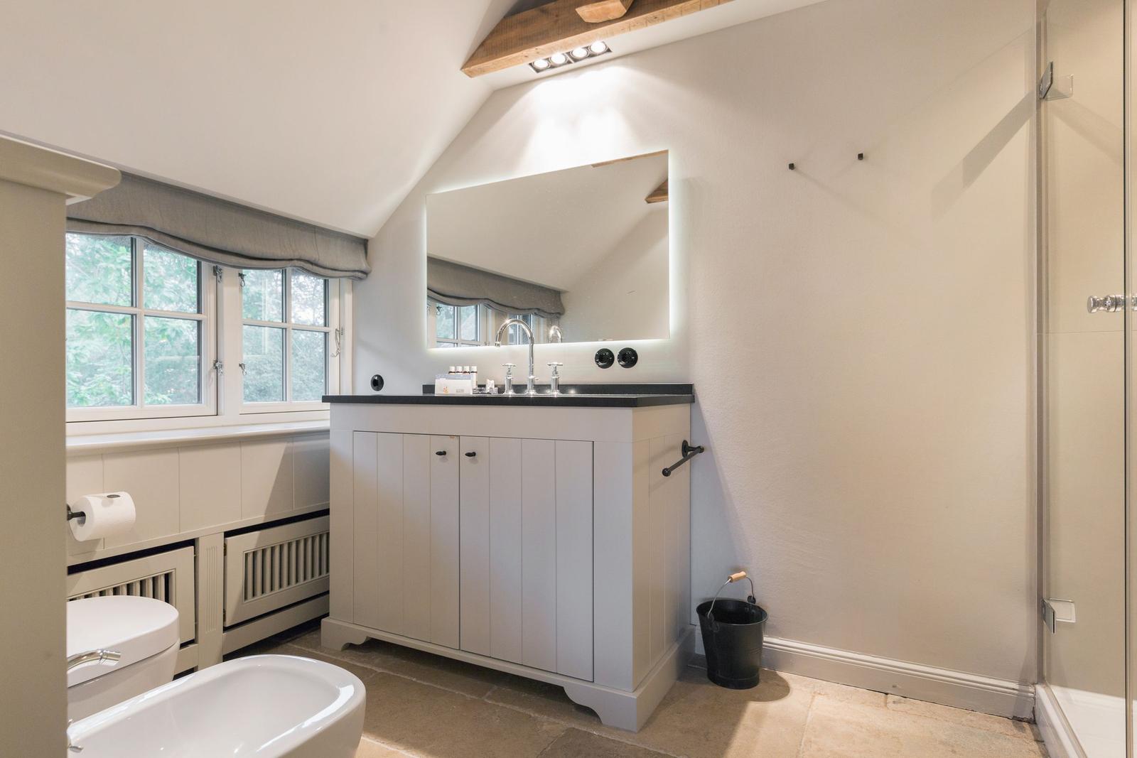 Badezimmer mit Waschtisch, Spiegel, Toilette und Badewanne unter einem Dach