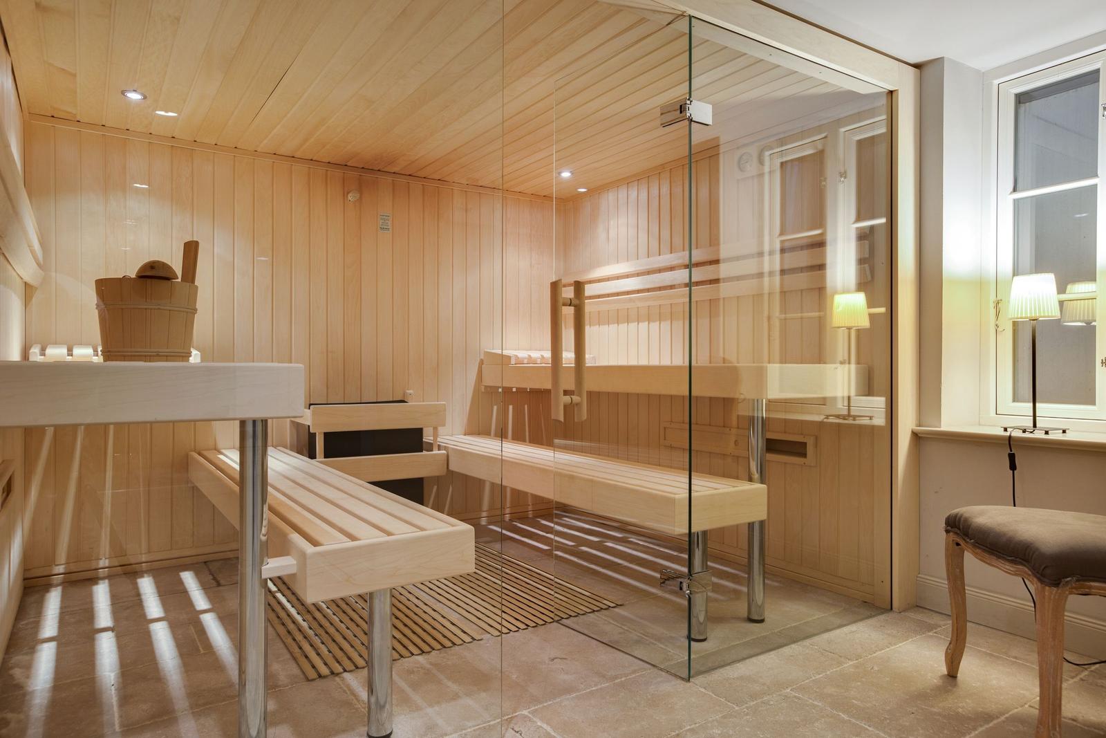 Sauna mit Holzbank und Glaswand. Fenster und Sitzbank im Vordergrund.