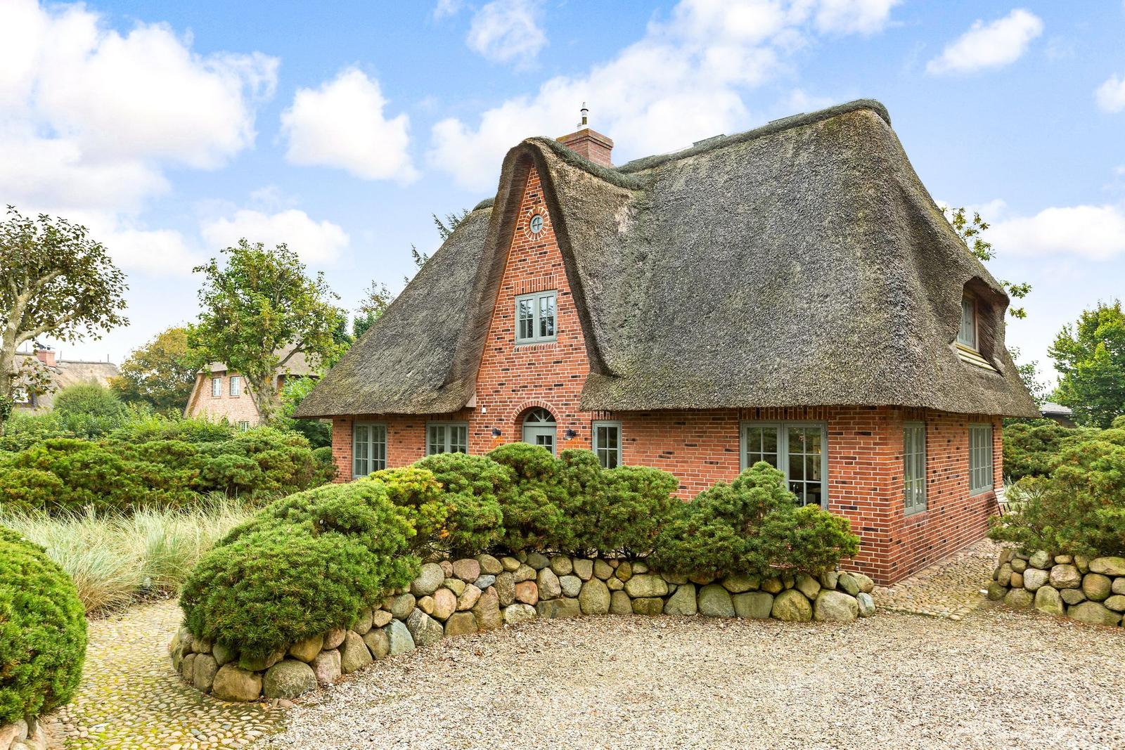 Haus mit Strohdach und Steinmauer im Garten