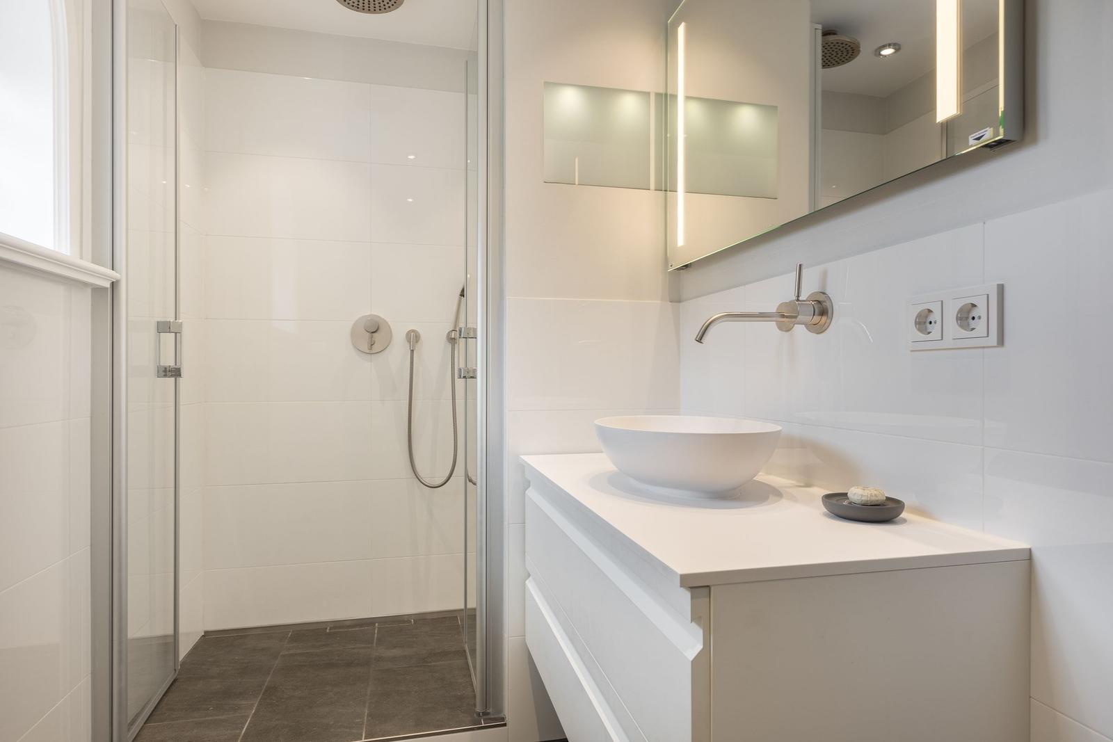 Bathroom with shower, sink, and mirror