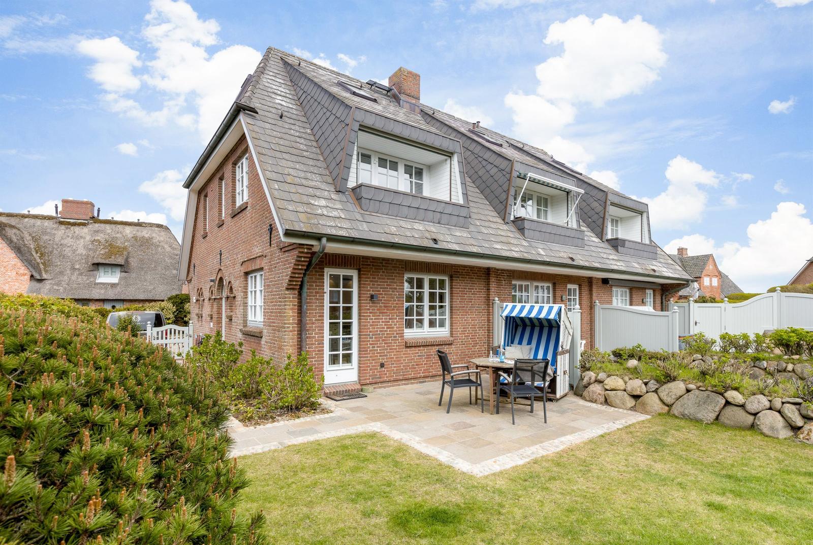 A red brick house with balcony and terrace in the garden