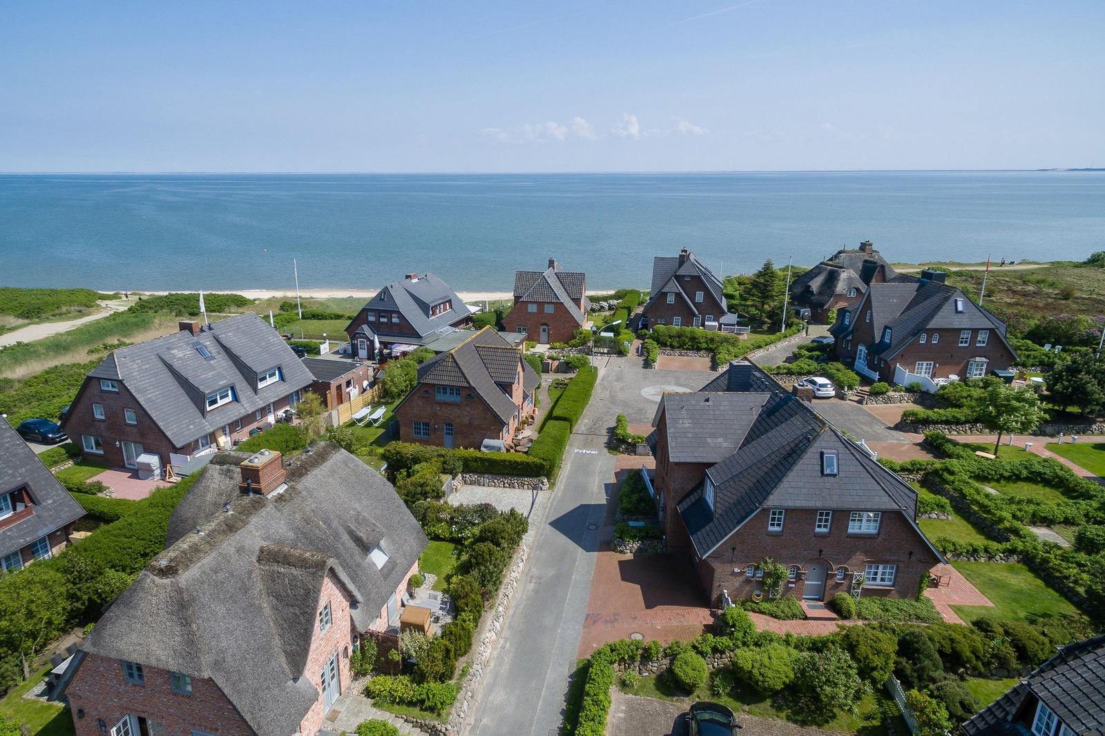 View of beach and houses with tiled and thatched roofs