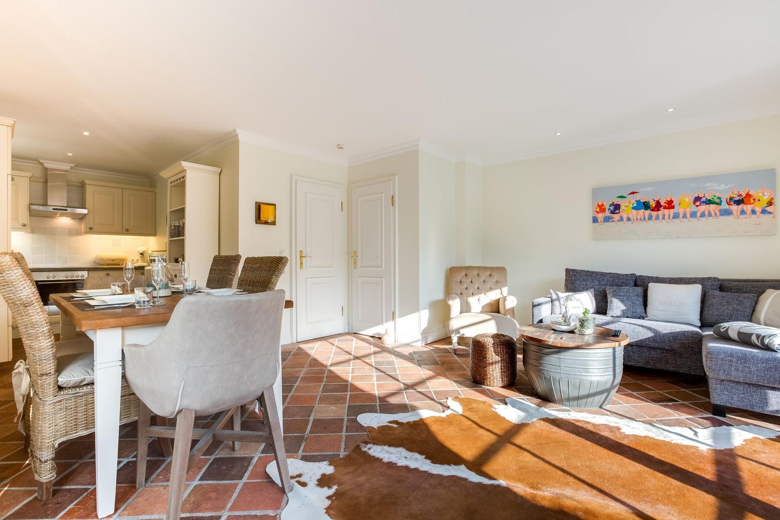 Wohn- und Essbereich mit Terrakottaboden, Sofa, Esstisch und Wandbild.