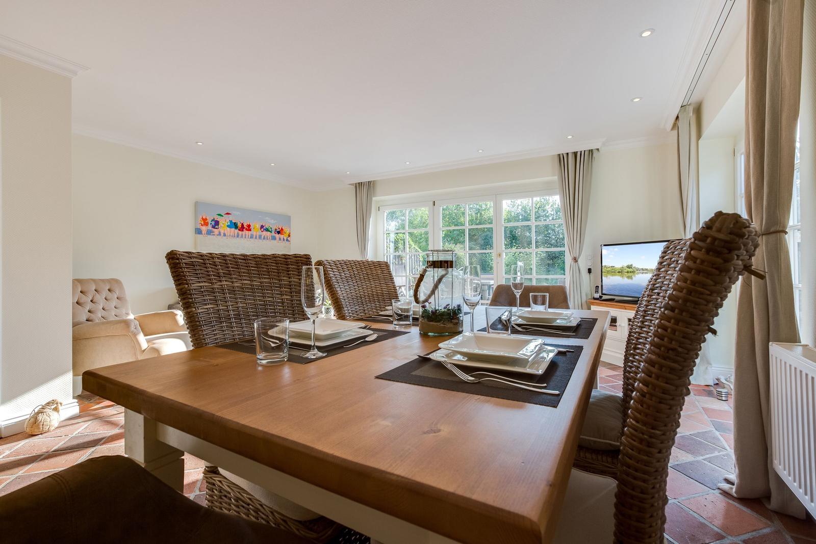 Esszimmer mit Holztisch, geflochtenen Stühlen und Blick auf den Garten.