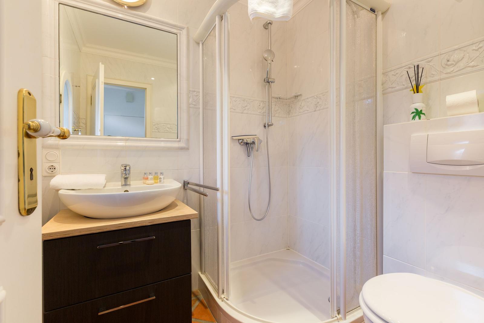 Badezimmer mit Dusche, Waschbecken und Toilette.