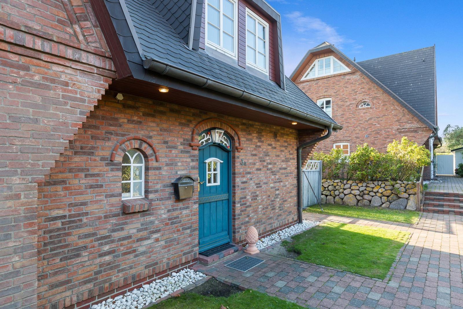 Rotes Backsteinhaus mit blauer Tür und gepflastertem Hof