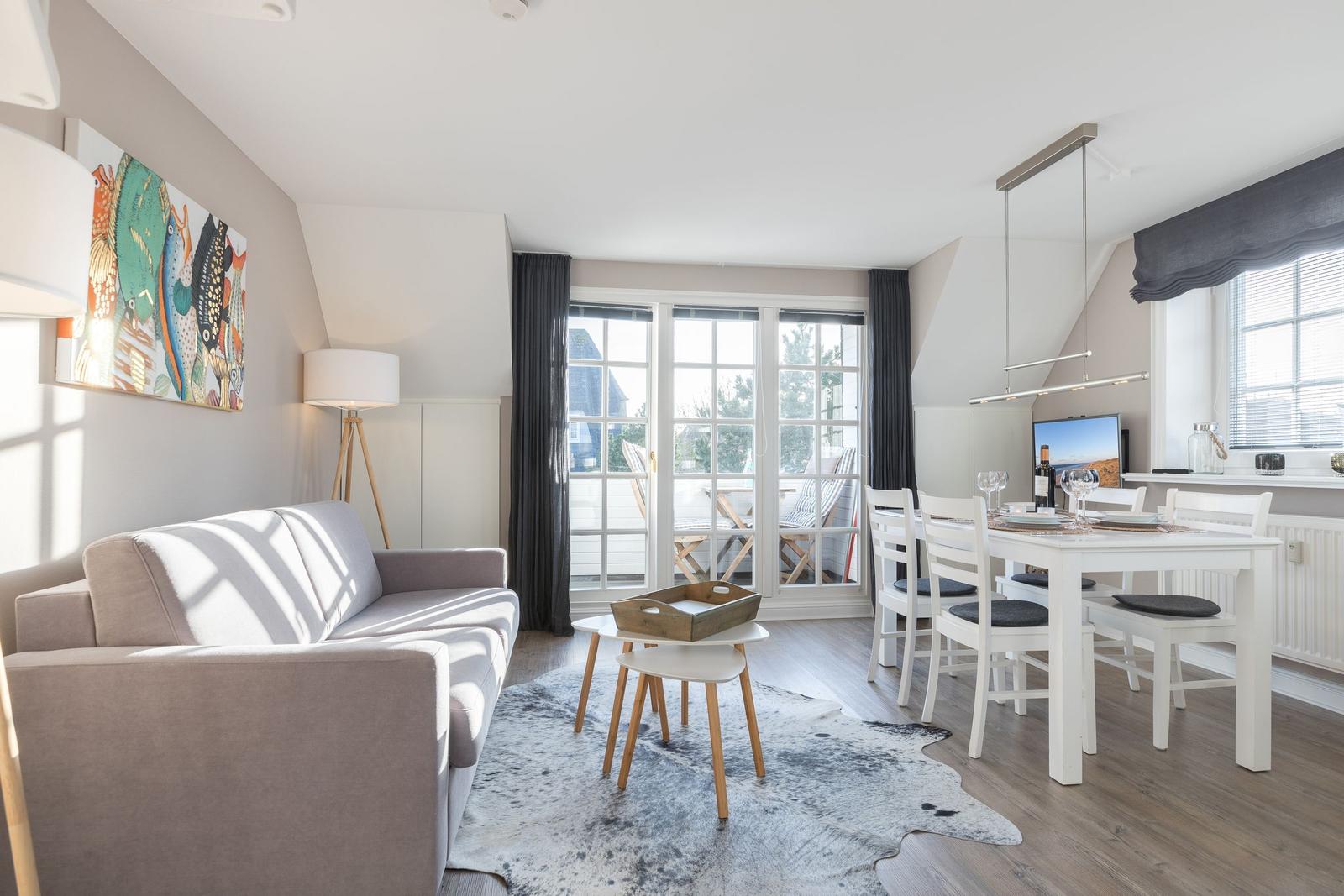 Living and dining area with sofa, table, and windows to the terrace.