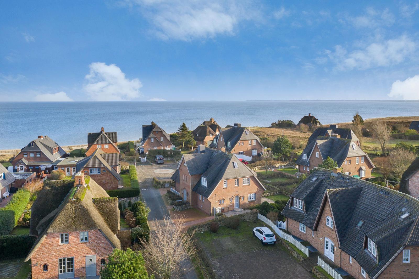 Thatched-roof houses by the sea under a blue sky