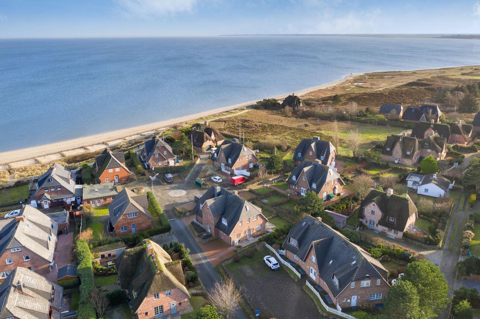 Village with houses by the coast, view of the sea and beach.