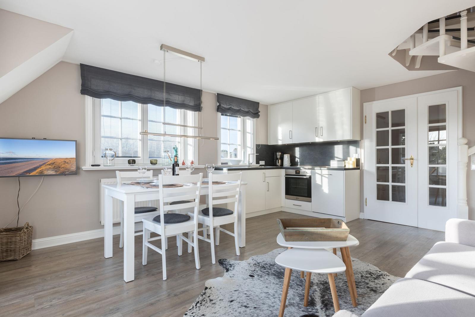 Kitchen with dining table, TV, and bedroom in background