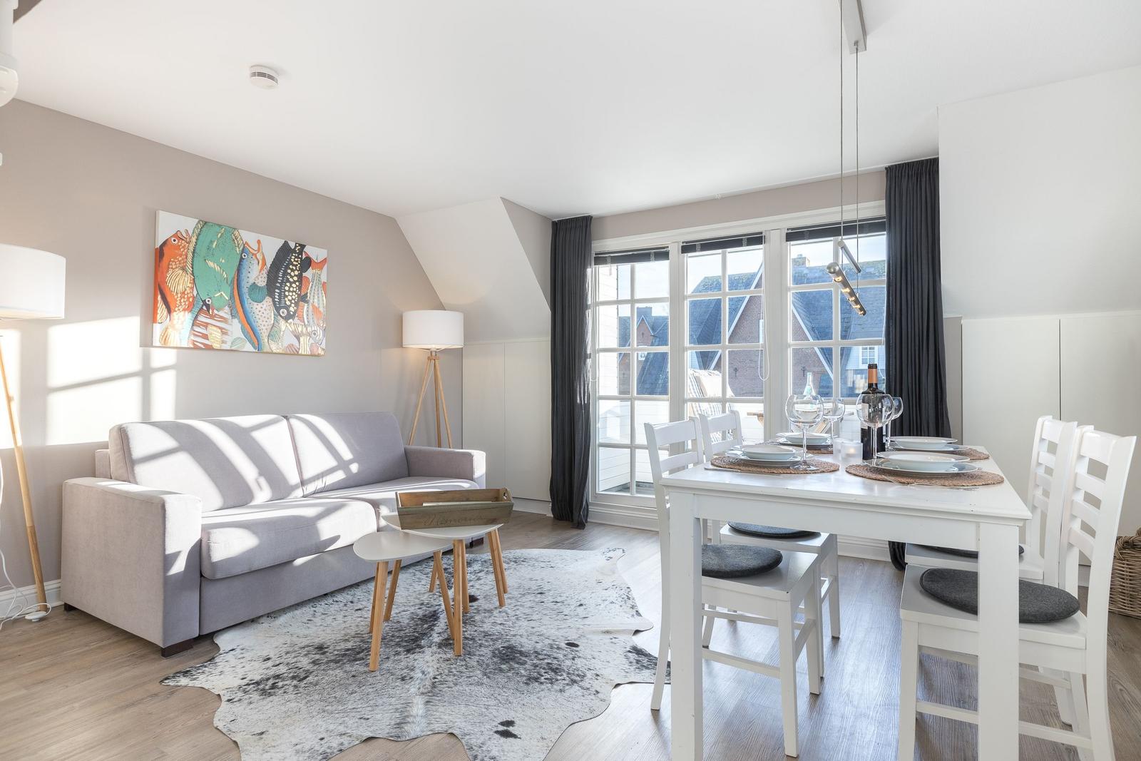 Living and dining area with sofa, dining table, and windows for views.