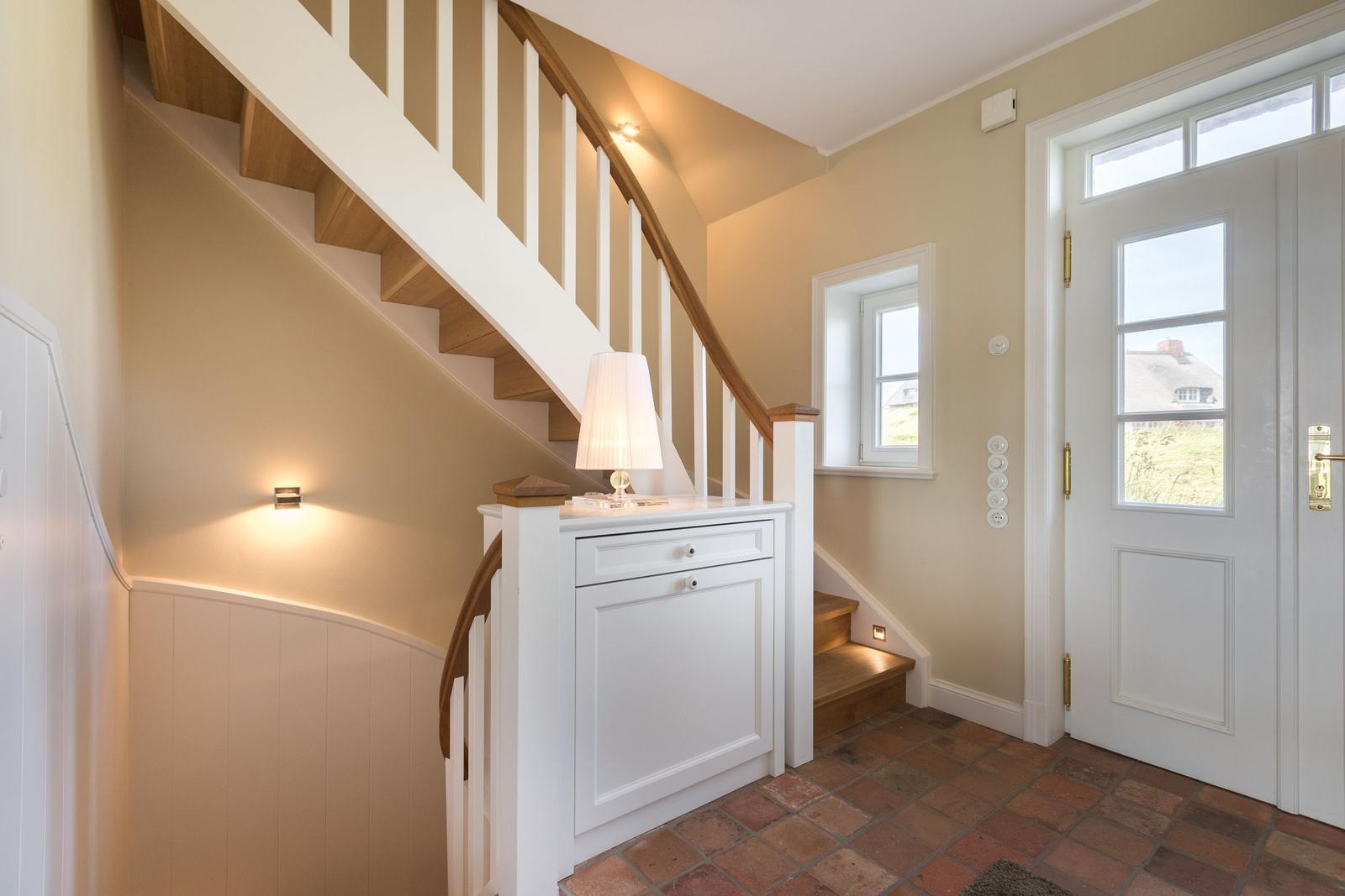 Eingang mit Treppe, weißer Schrank und Terrakottboden.