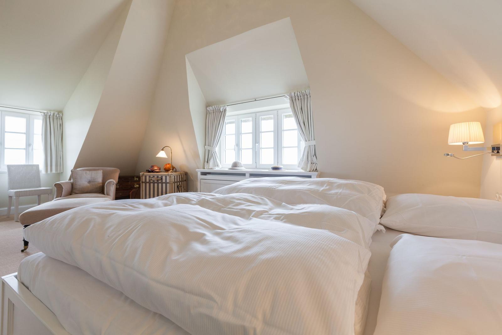 Schlafzimmer mit Doppelbett, Fenster und Sessel.