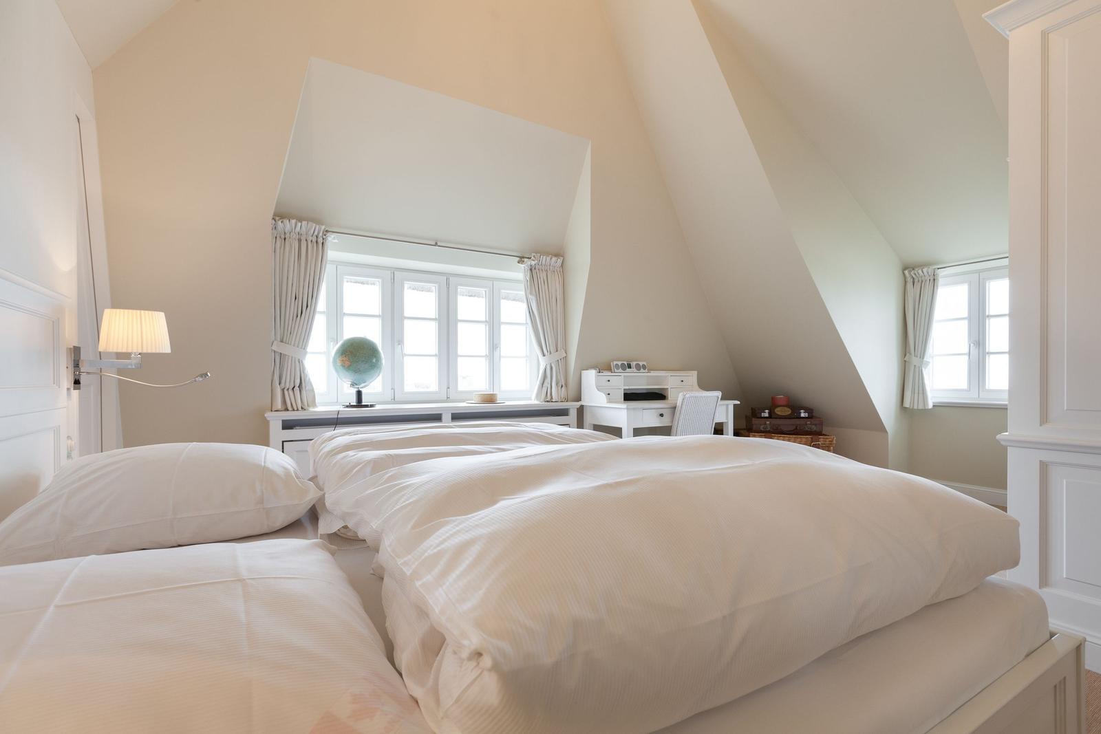 Schlafzimmer mit Dachschrägen, Fenster, Schreibtisch und Globus.
