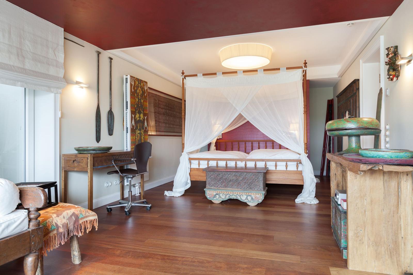 Schlafzimmer mit Bett, Schreibtisch und Holzboden.
