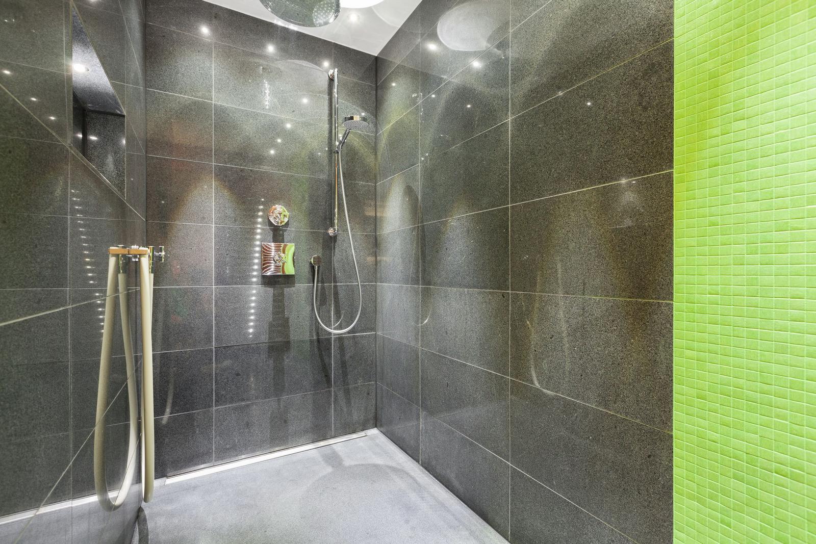 Dusche mit grauen Fliesen und grüner Mosaikwand