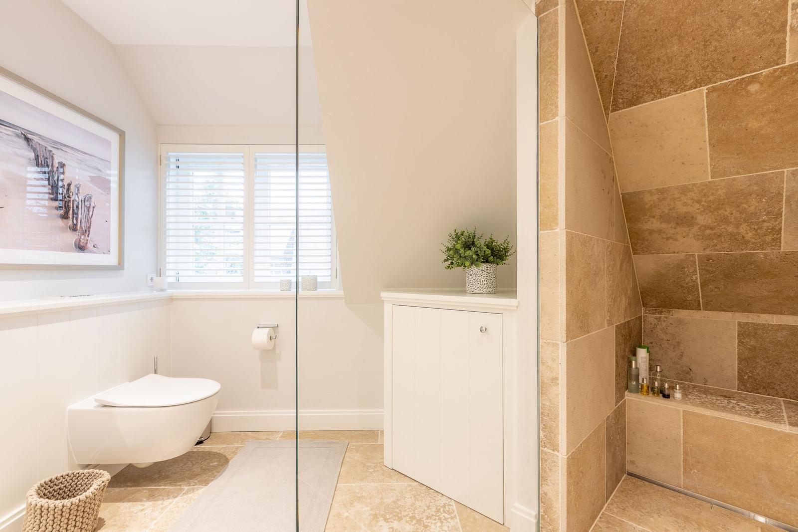 Badezimmer mit Toilette, Dusche und Fenster mit Jalousie