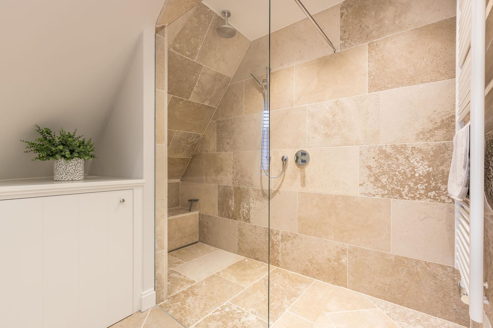 Duschkabine mit Glaswand, Steinfliesen und Handbrause