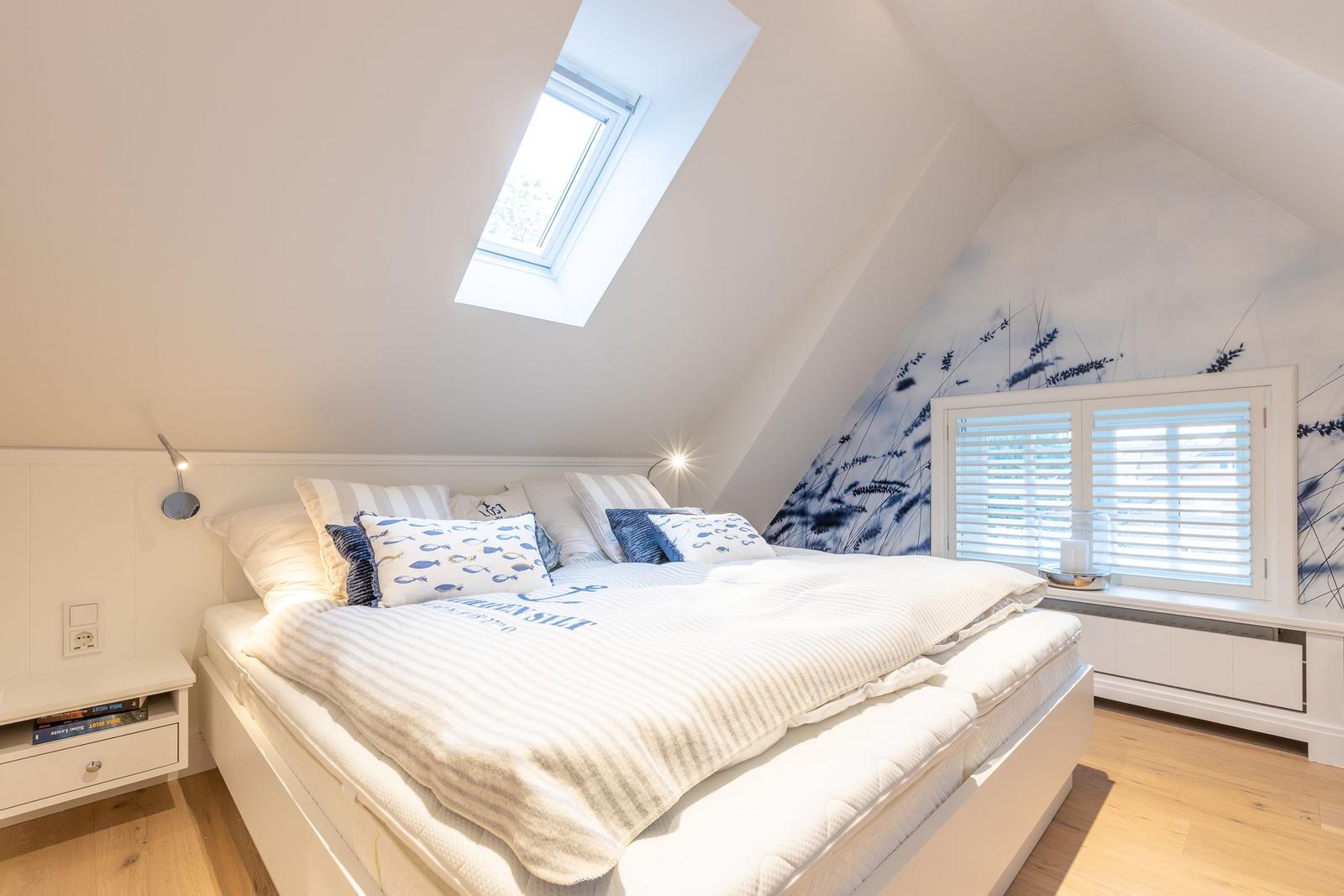 Schlafzimmer mit Dachschrägen, Dachfenster und Fenster mit Jalousie.