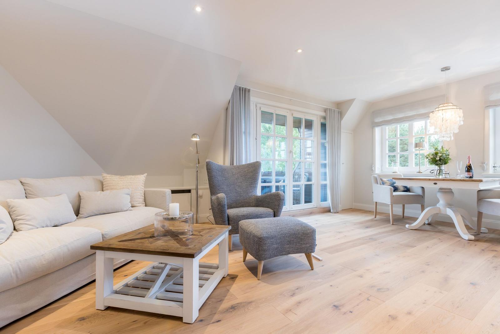 Wohn- und Essbereich mit Sofa, Sessel und Holzboden.