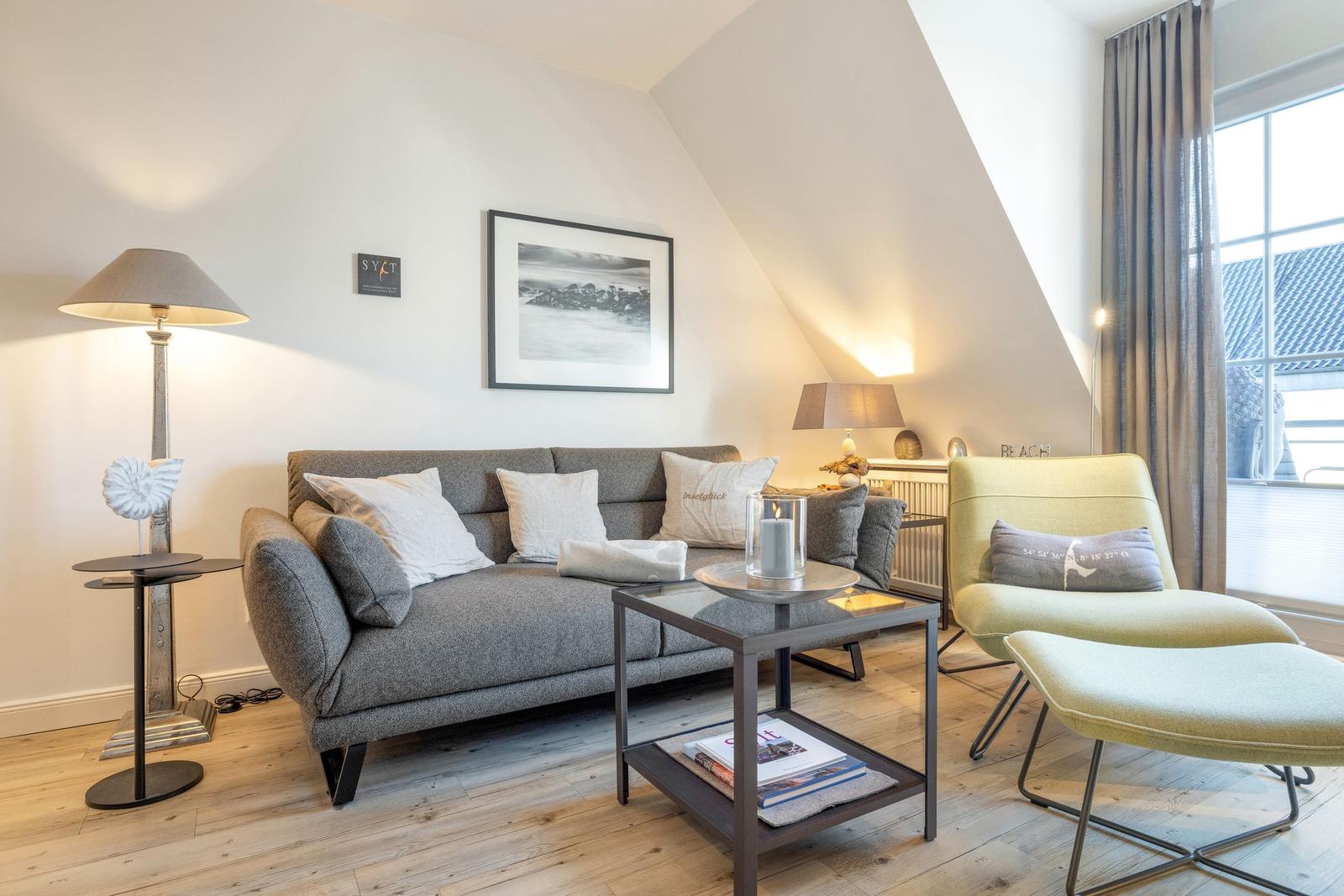 Living room with sofa, armchair, and coffee table under sloped ceiling.