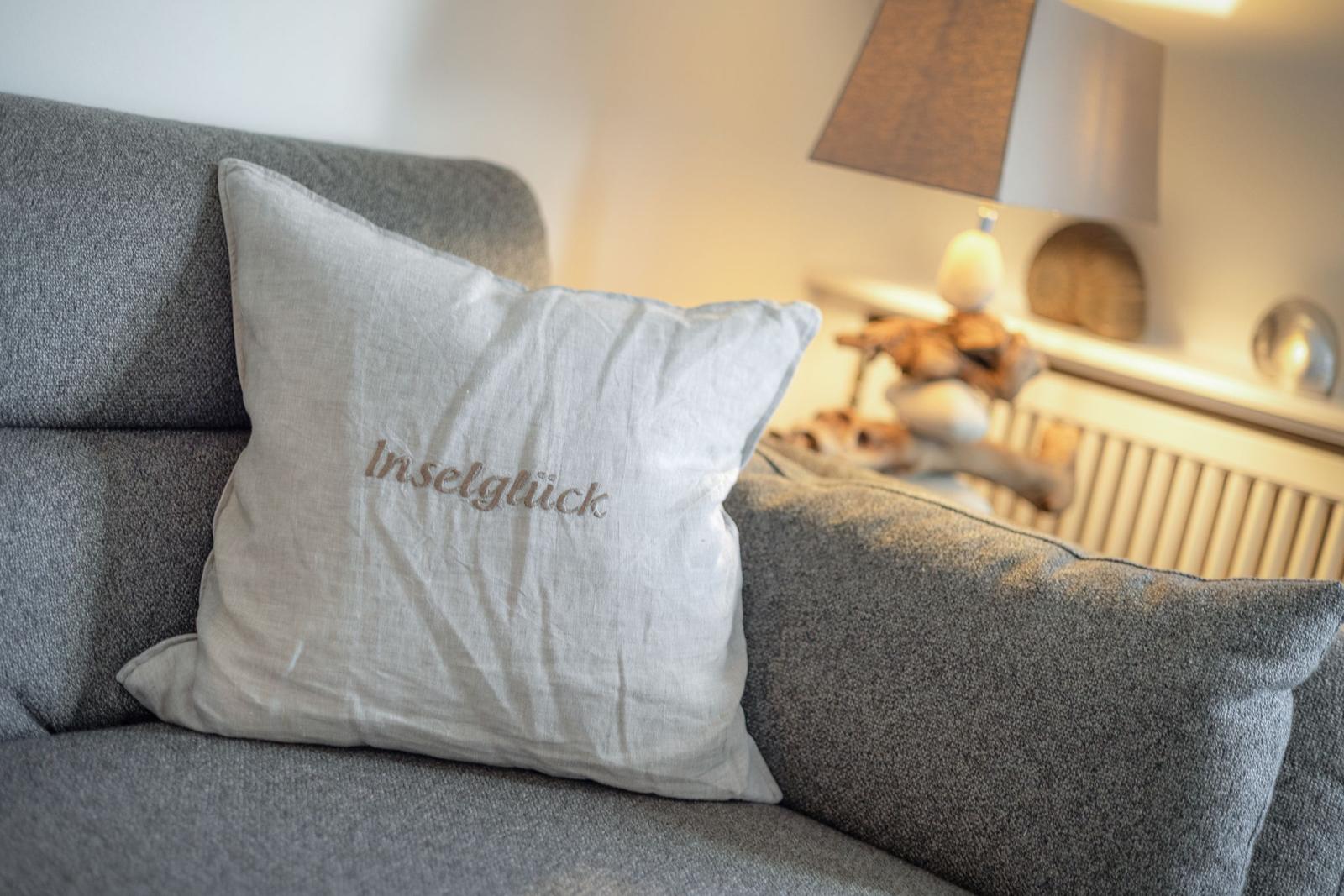 A gray sofa with a pillow that reads Inselglück.