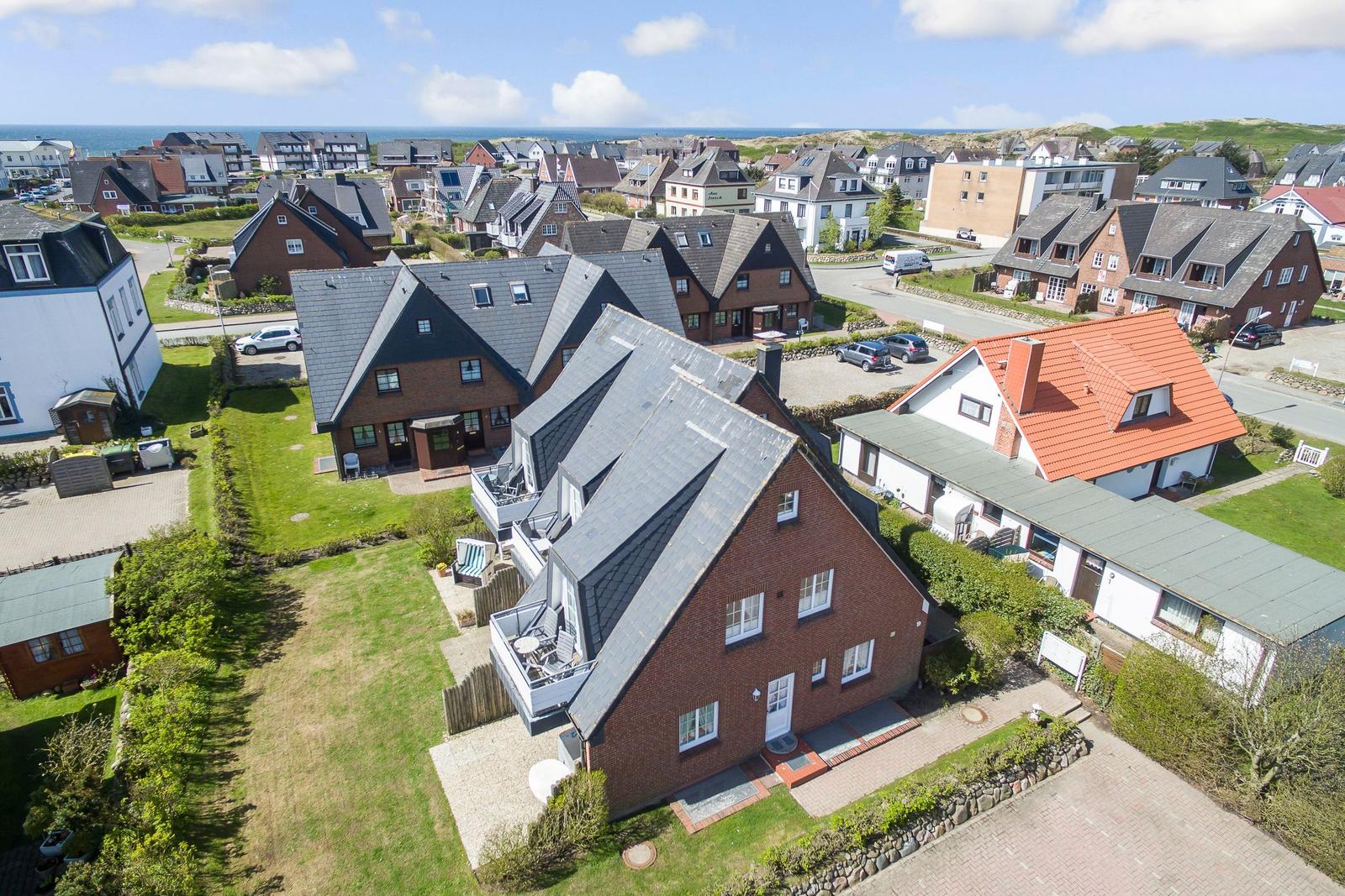 House with garden and terrace, view of coastal town with sea in background.