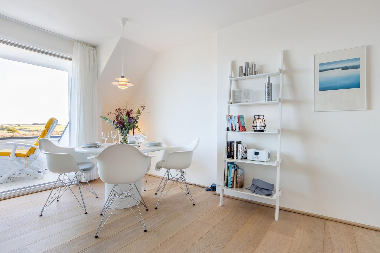 Essbereich mit Tisch, Stühlen und Bücherregal an der Wand.