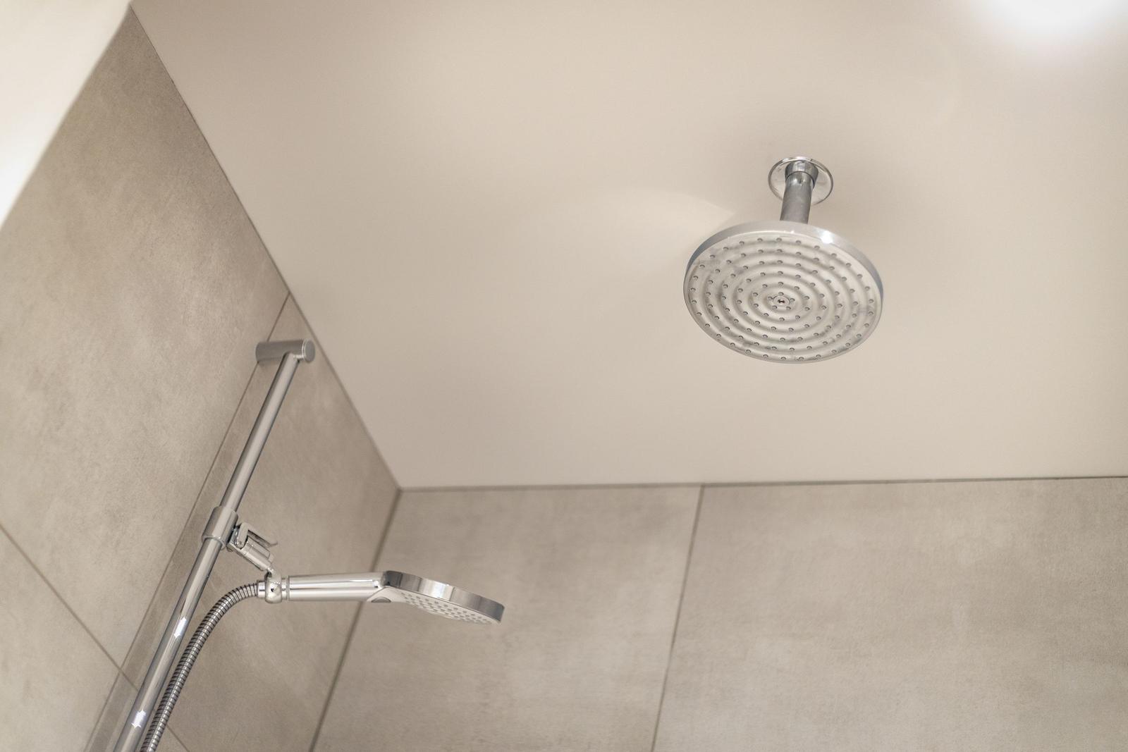 Duschkopf an der Decke und Handbrause im Duschbereich.