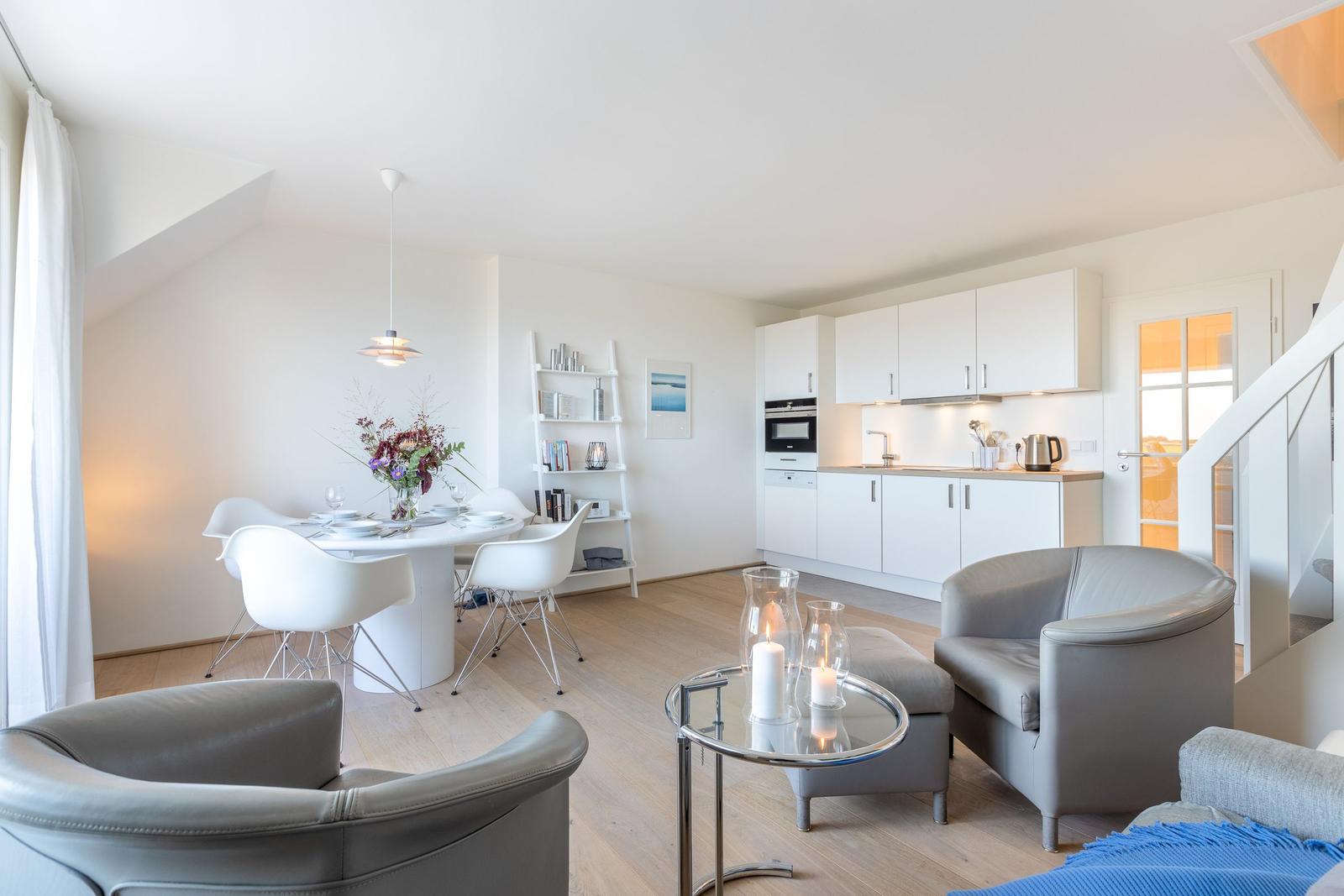 Wohnküche mit Esstisch, zwei Sesseln und einer Glasplatte.