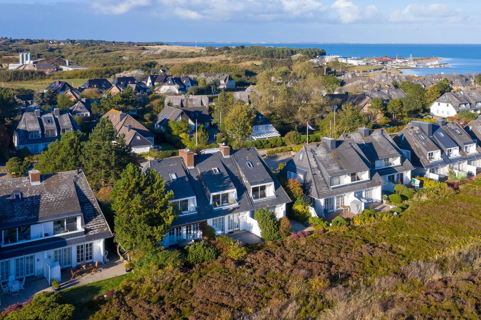 Häuser mit Dächern und Gärten, Blick auf Meer und Hafen.