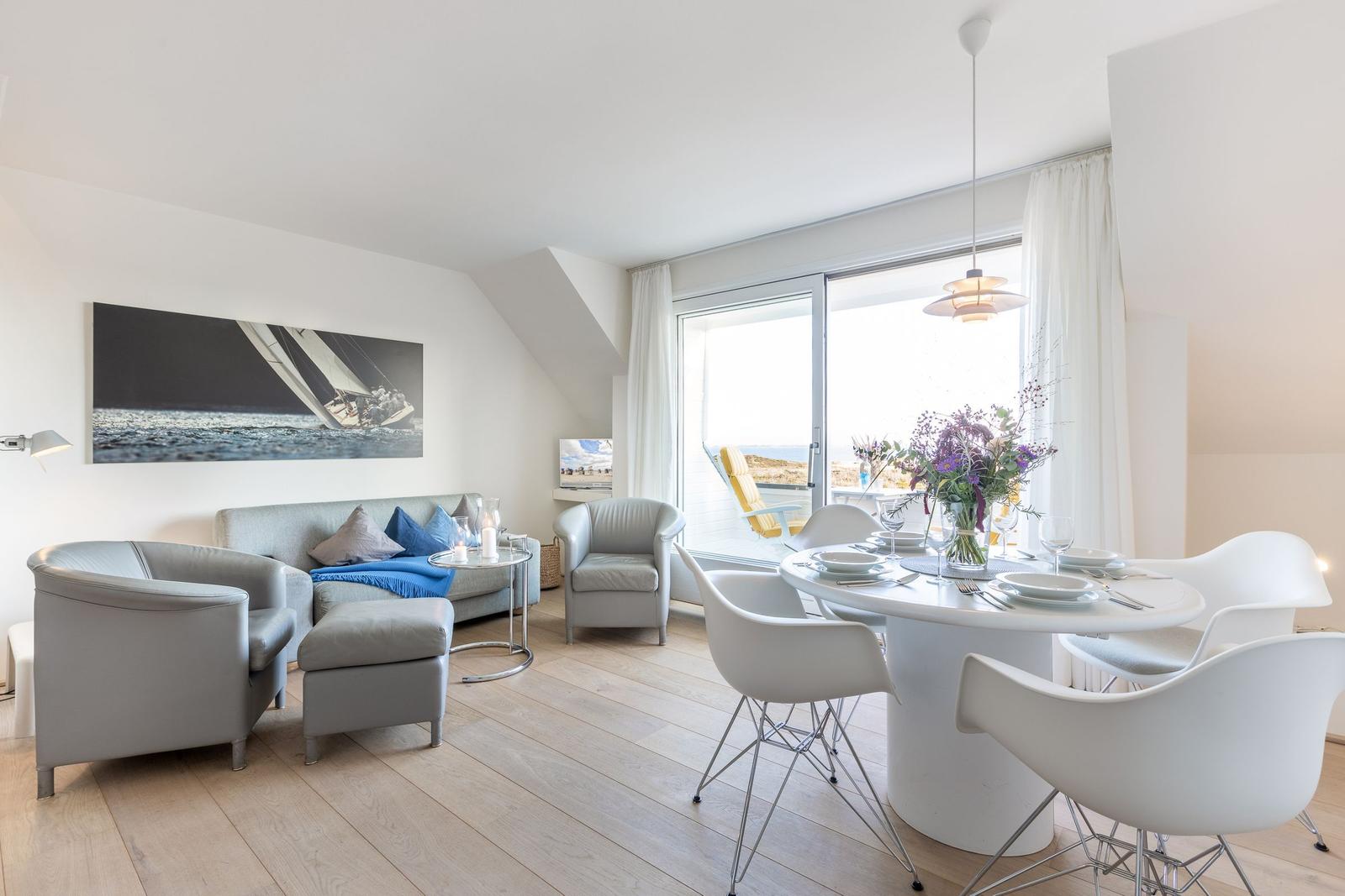 Wohn- und Essbereich mit Tisch, Stühlen und Sofa. Große Fensterfront mit Blick.