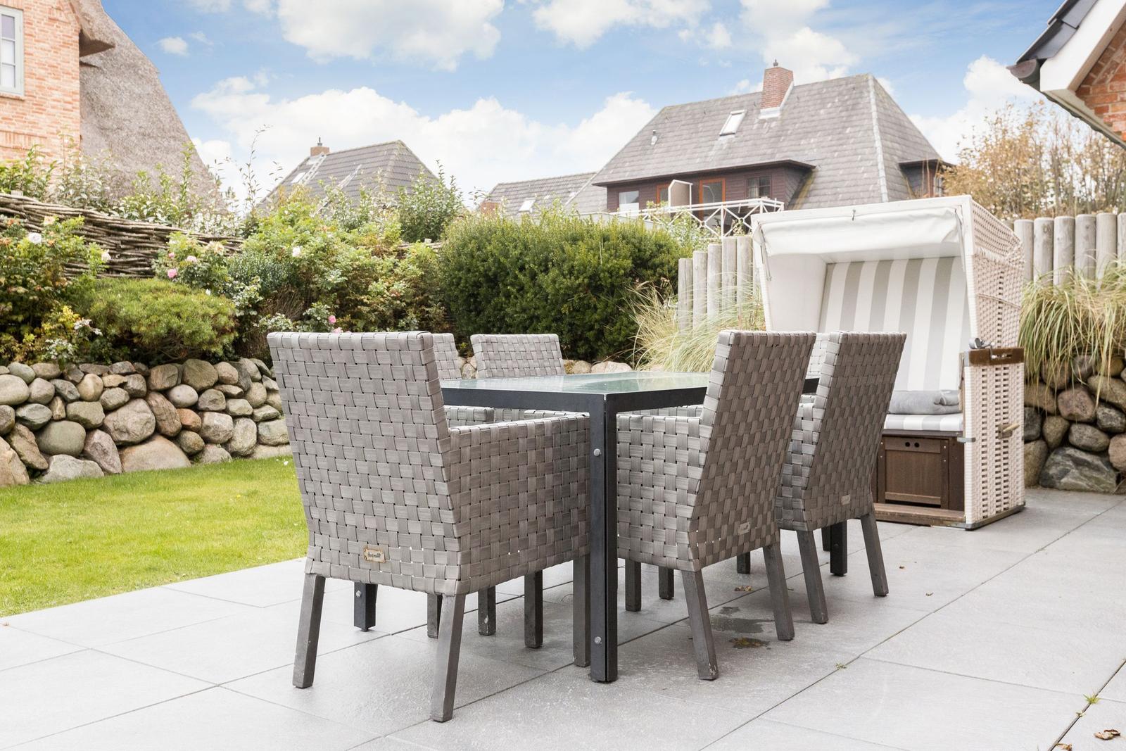 Terrasse mit Esstisch und Stühlen, Strandkorb und Garten.