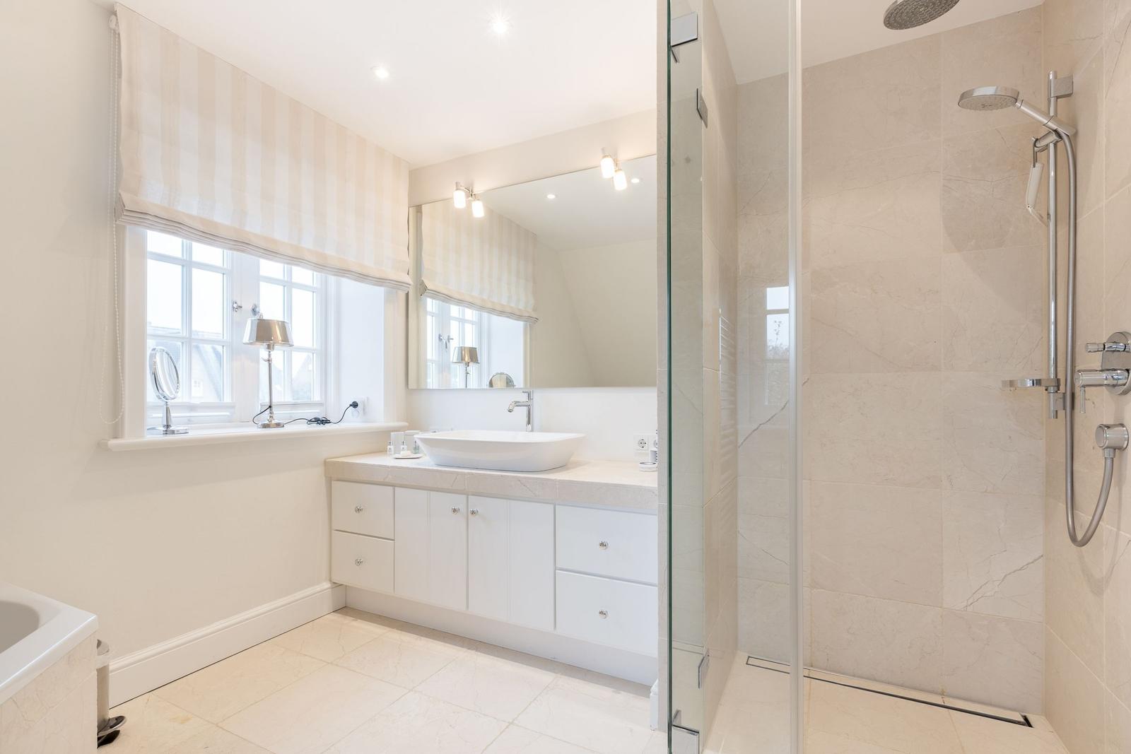 Badezimmer mit Dusche, Waschbecken und Fenster