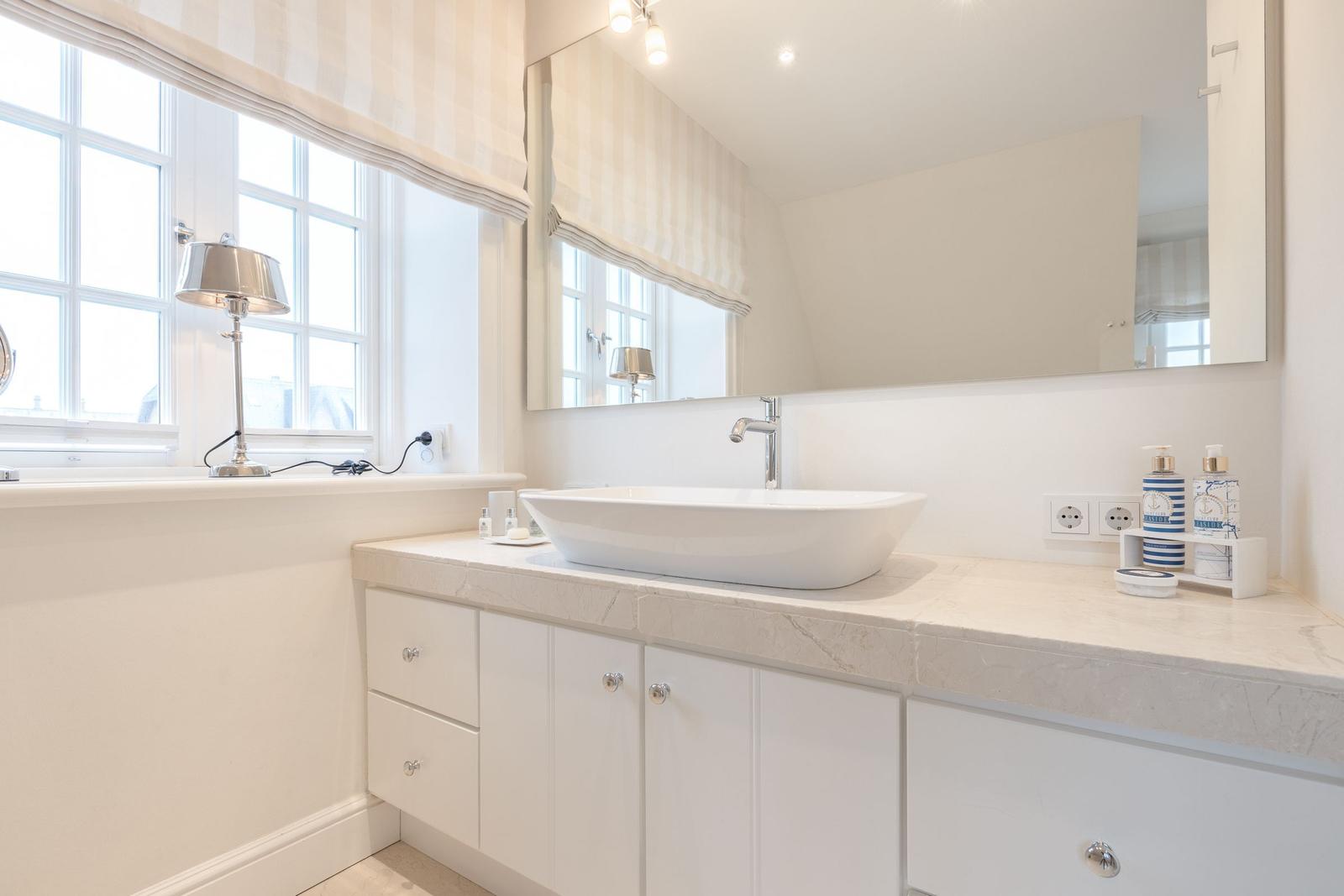 Badezimmer mit Waschbecken, Spiegel und Fenster