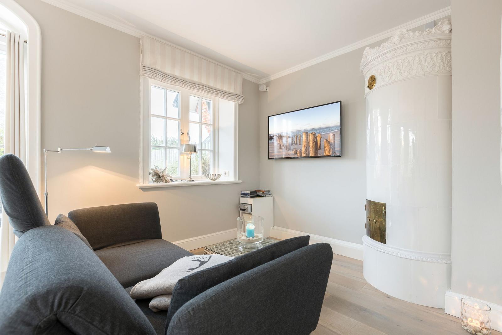Wohnzimmer mit Sofa, Fernseher und weißem Kamin.