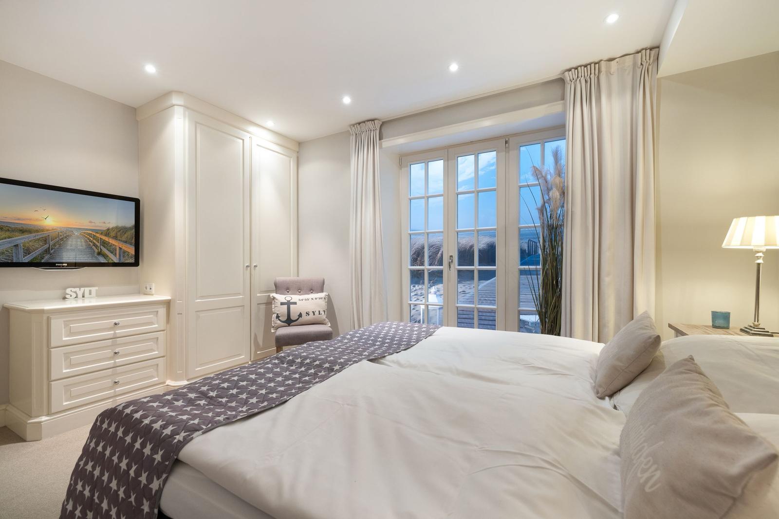 Schlafzimmer mit Bett, TV und Fenster zur Aussicht
