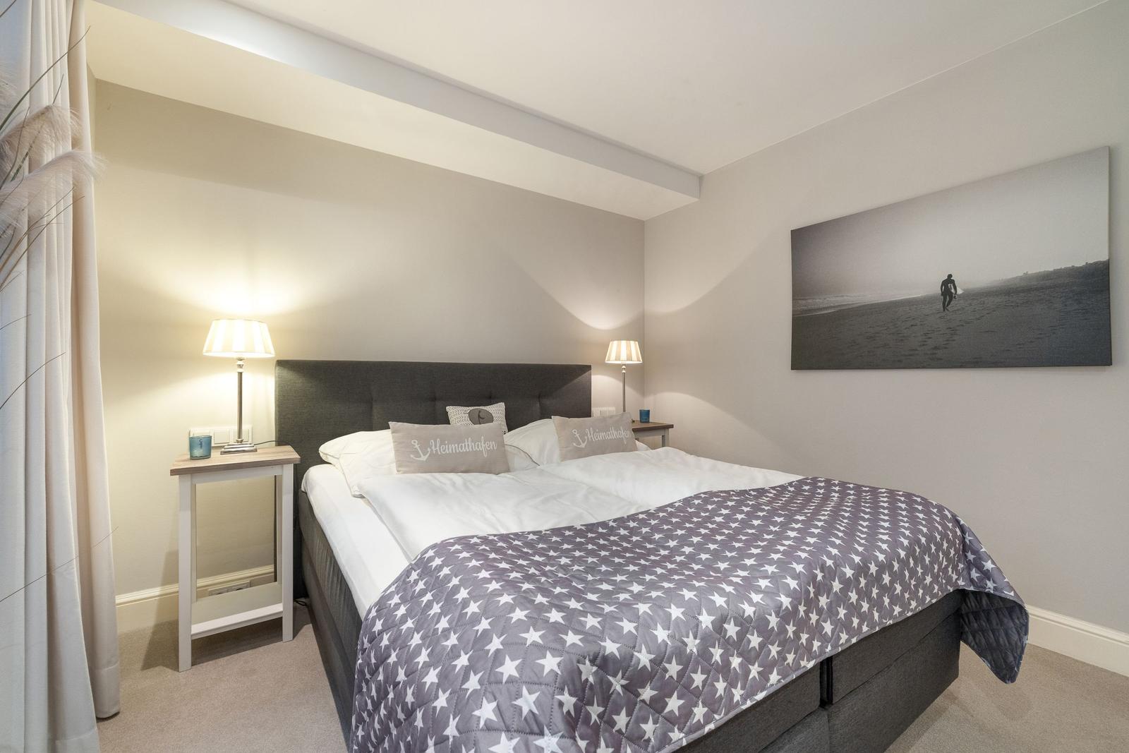 Schlafzimmer mit Doppelbett, Nachttischen und Wandbild.