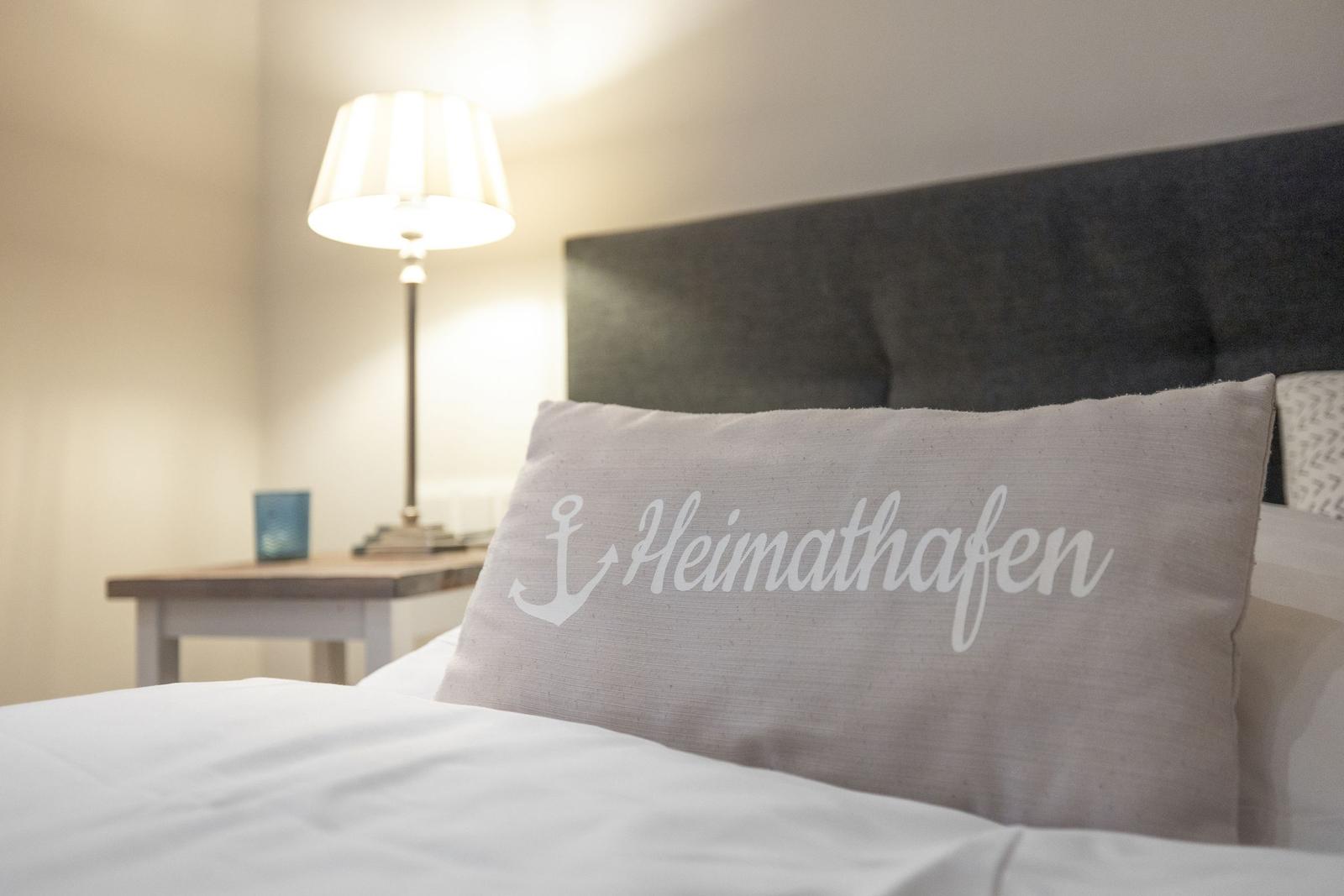 Bettkopfteil mit Kissen, das Heimathafen schreibt.