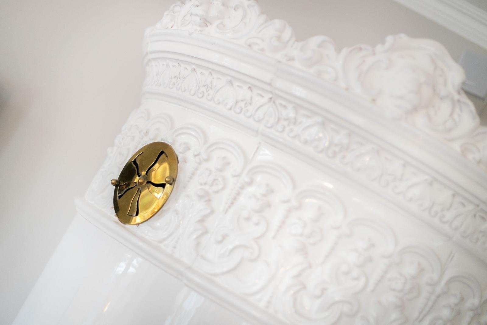 Weiße, verzierte Wand mit goldenem Ventil