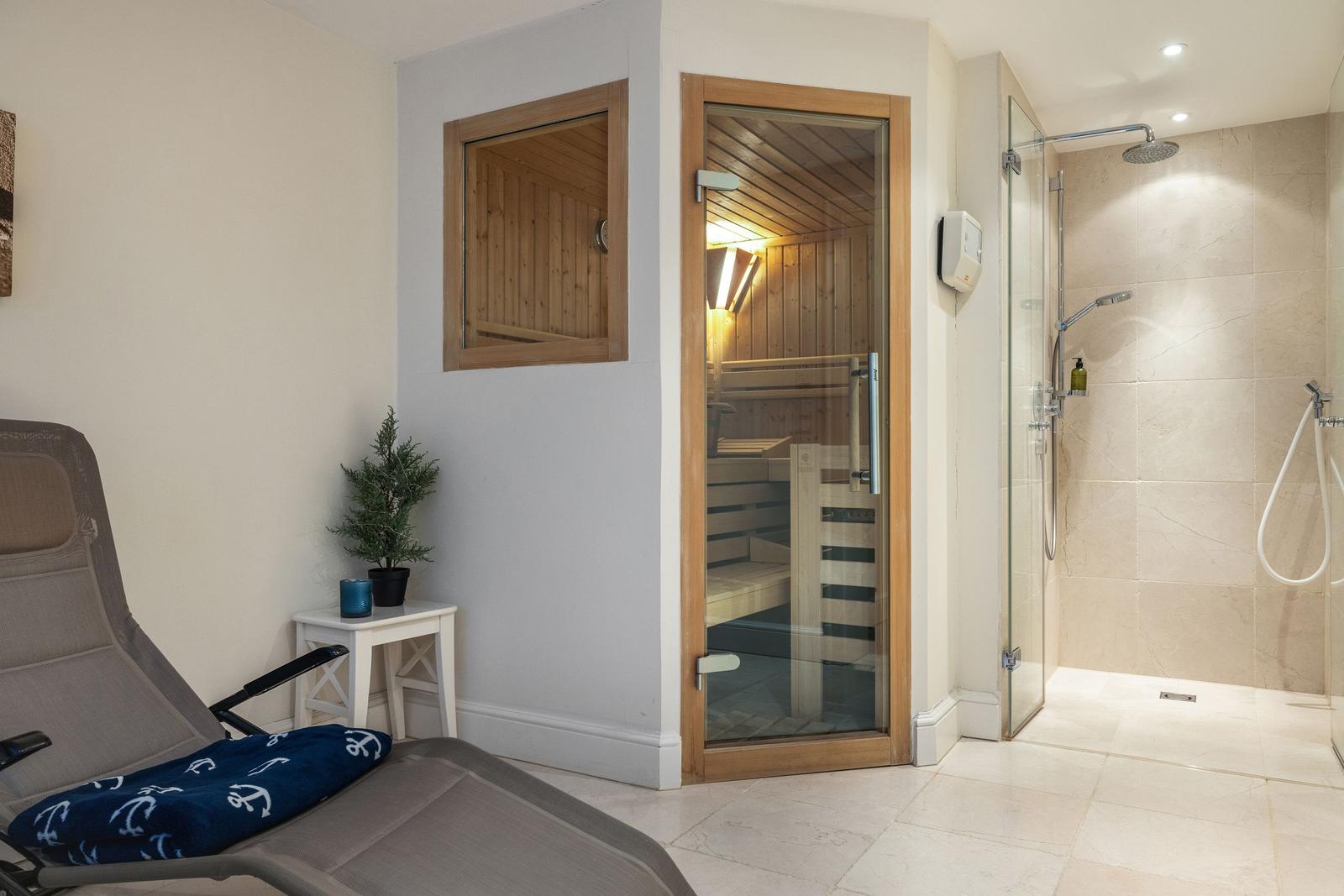 Sauna mit Glaswand, Dusche und Liege im Bad