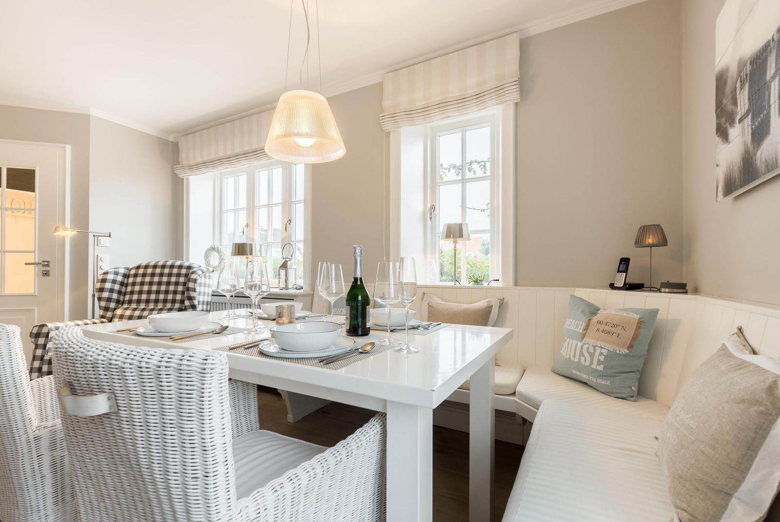 Esszimmer mit weißem Tisch, weißen Stühlen und Fenstern mit Raffstoren.