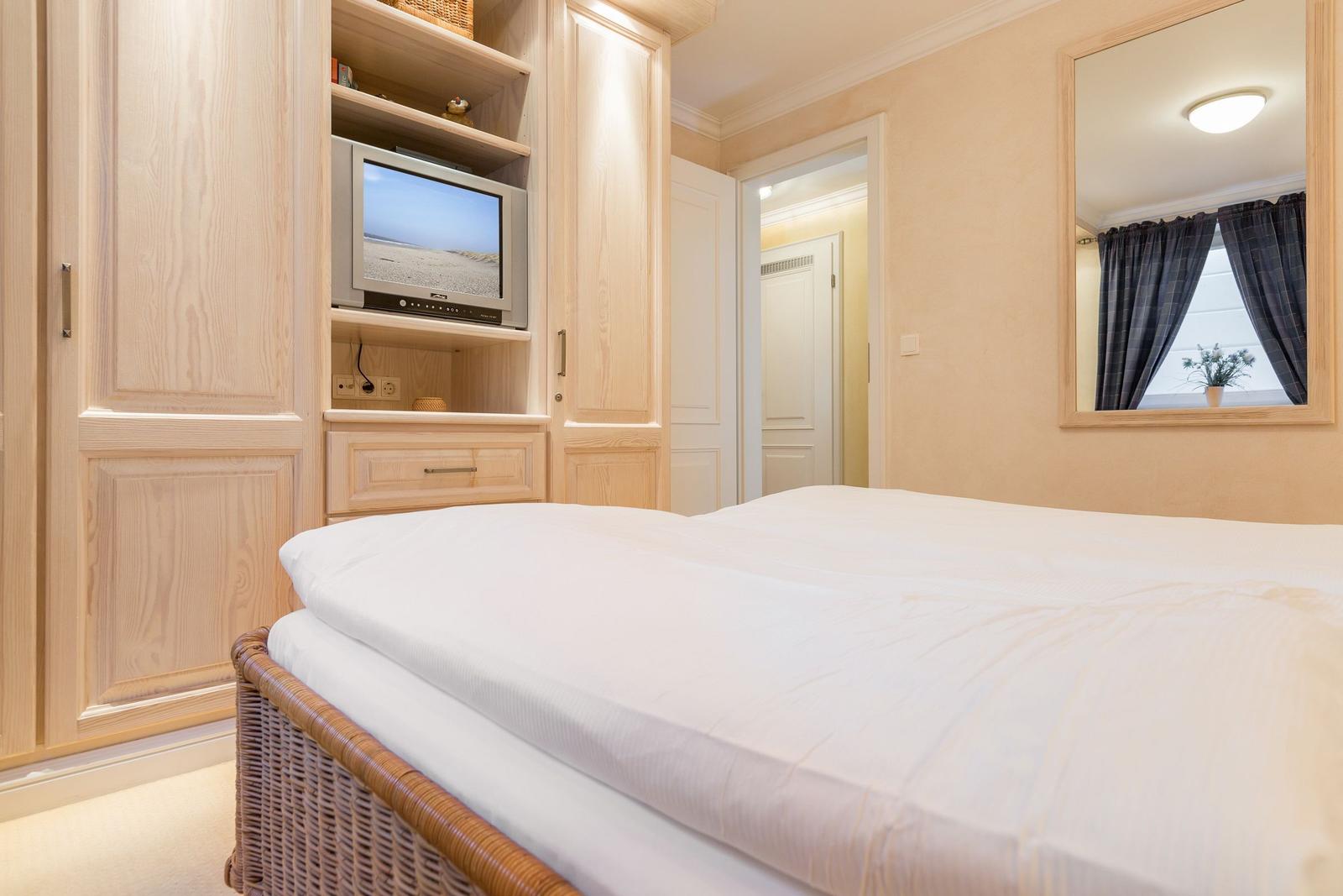 Schlafzimmer mit Bett, Kleiderschrank und Fernseher.