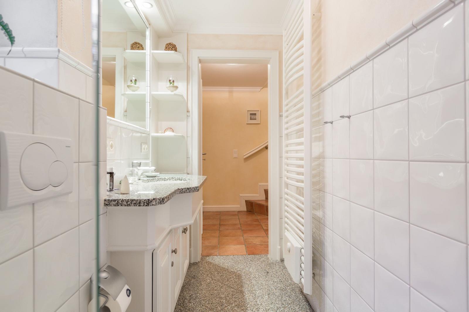 Badezimmer mit Waschbecken, Spiegel und Heizkörper