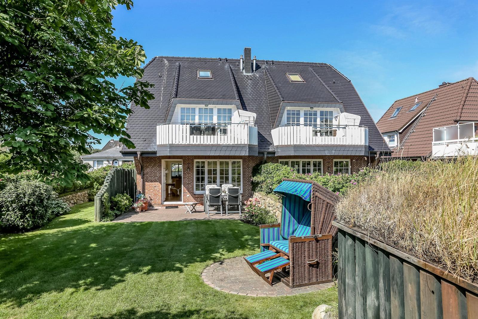 Haus mit Garten, Terrasse und Strandkorb. Zwei Balkone und großer Rasenbereich.