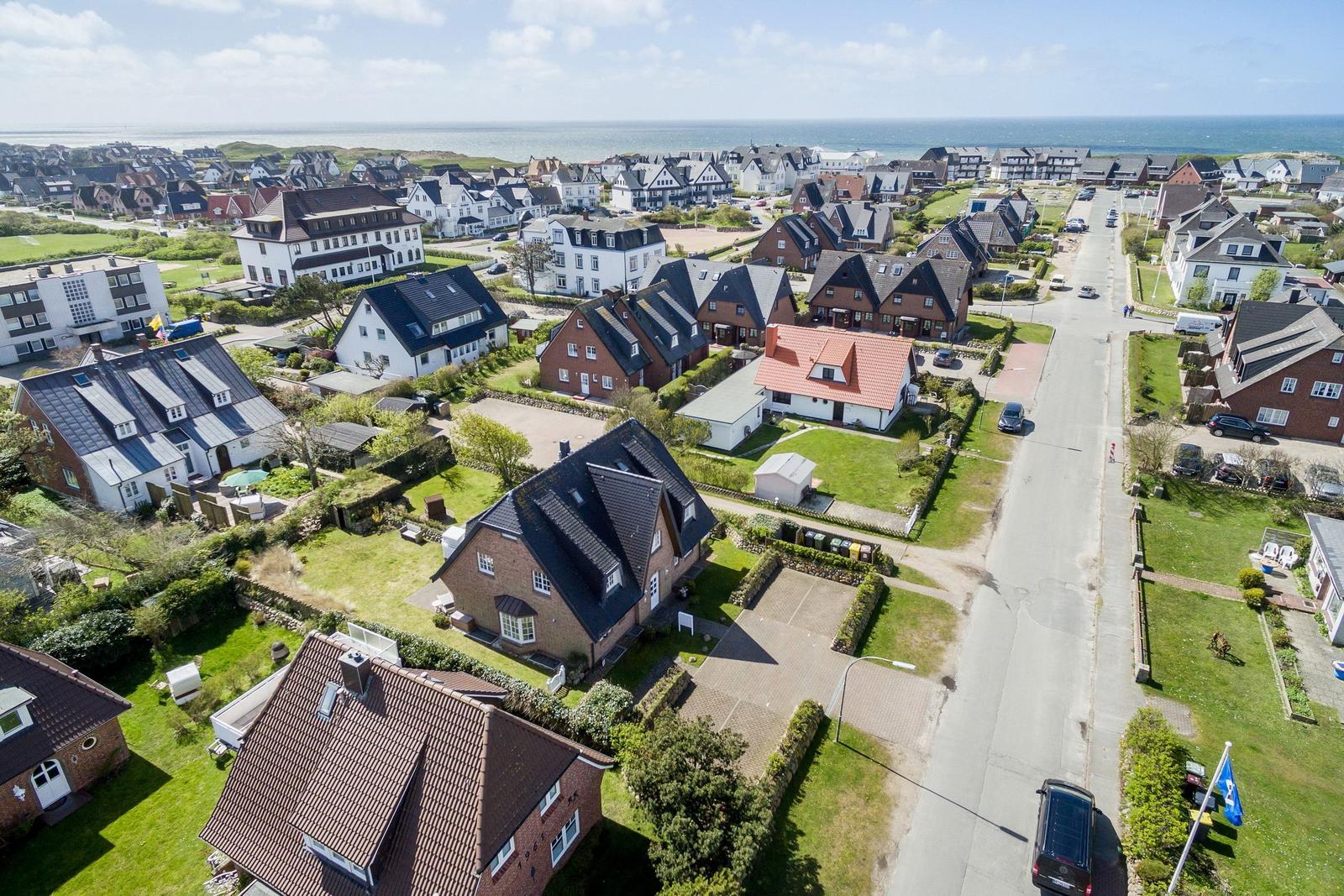 Aerial view of a coastal village with houses and green lawns near the sea.