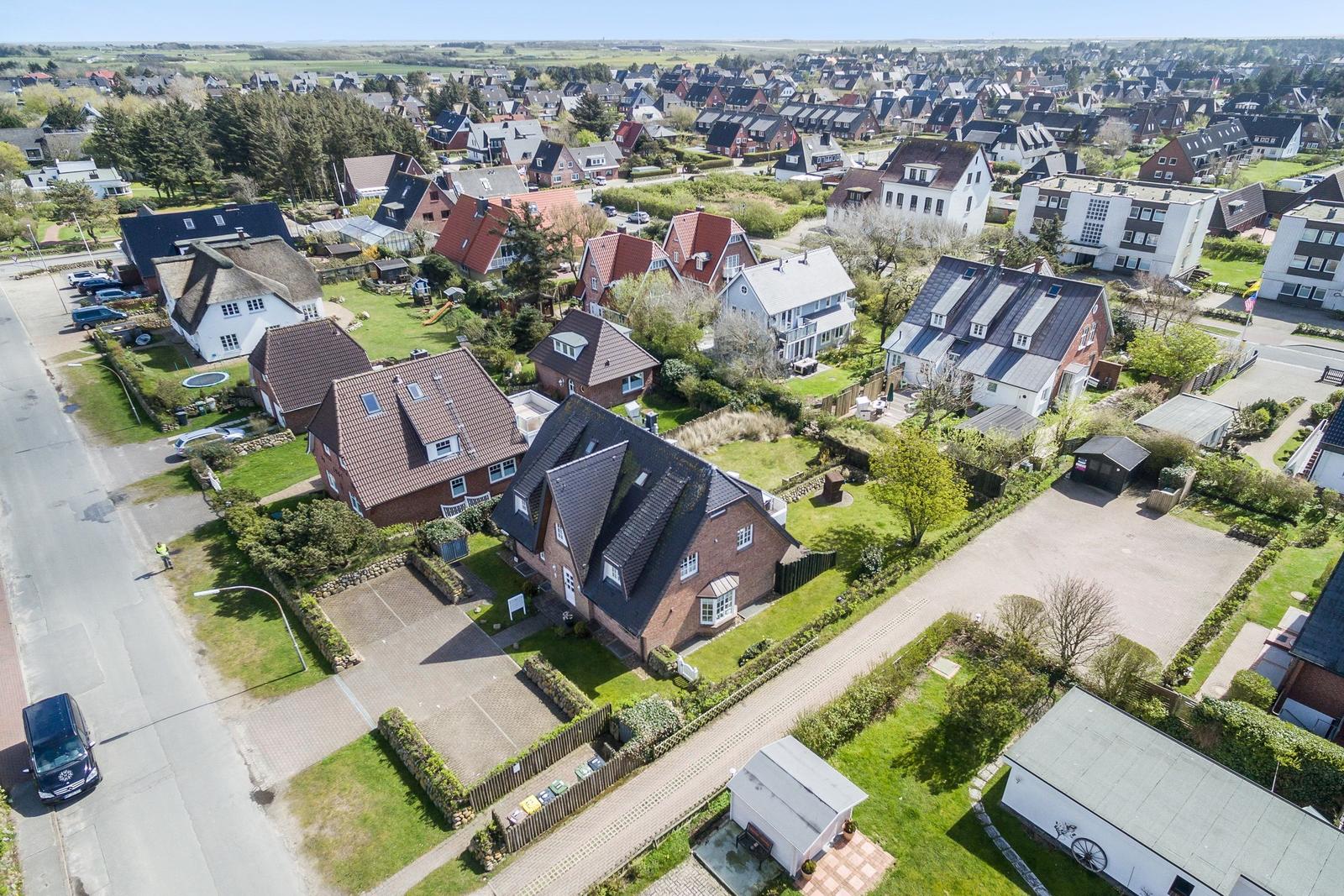 Luftbild eines Wohngebiets mit Häusern, Grünflächen und Straßen.