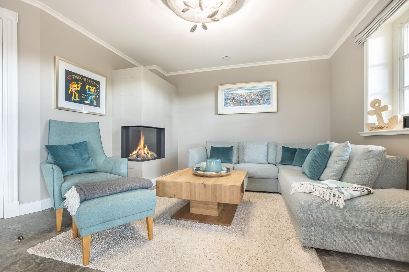 Wohnzimmer mit Sofa, Sessel, Kamin und Holztisch.